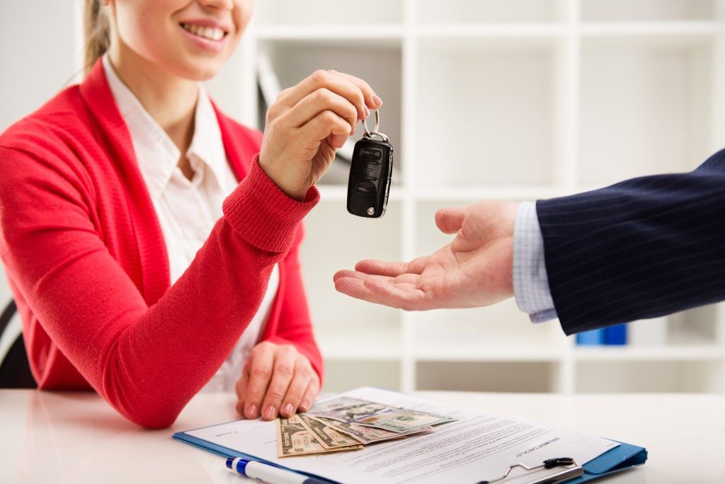 Woman giving car keys to buyer