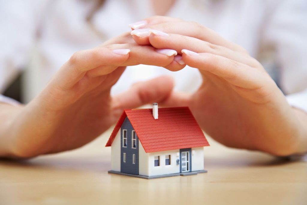 hand hovering over miniature house model
