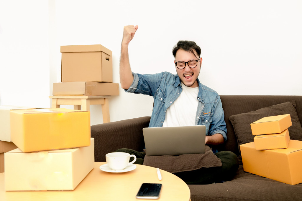 entrepreneur using his laptop while being surrounded by packages