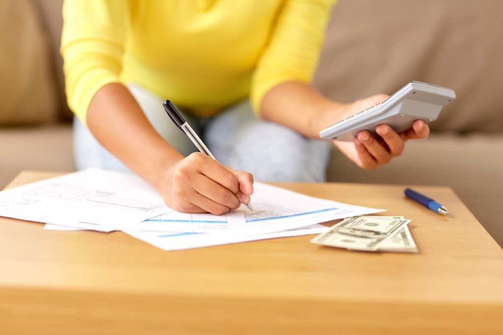A woman taking care of the budget and finance - holding a calculator while writing on a form