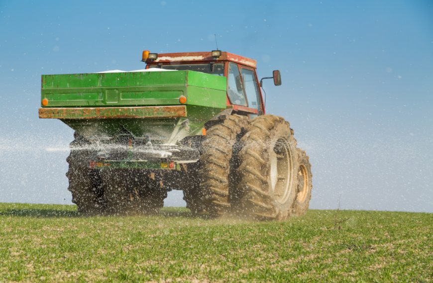 A truck carrying and spraying fertilizer on a field