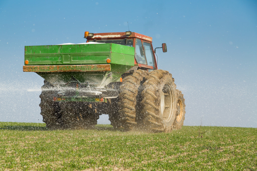 A truck carrying and spraying fertilizer on a field