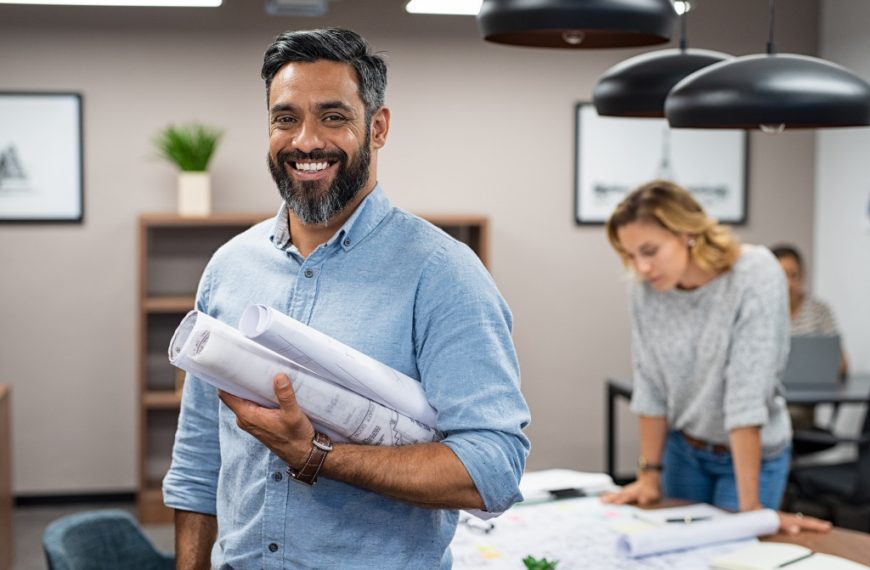 man smiling holding blue prints