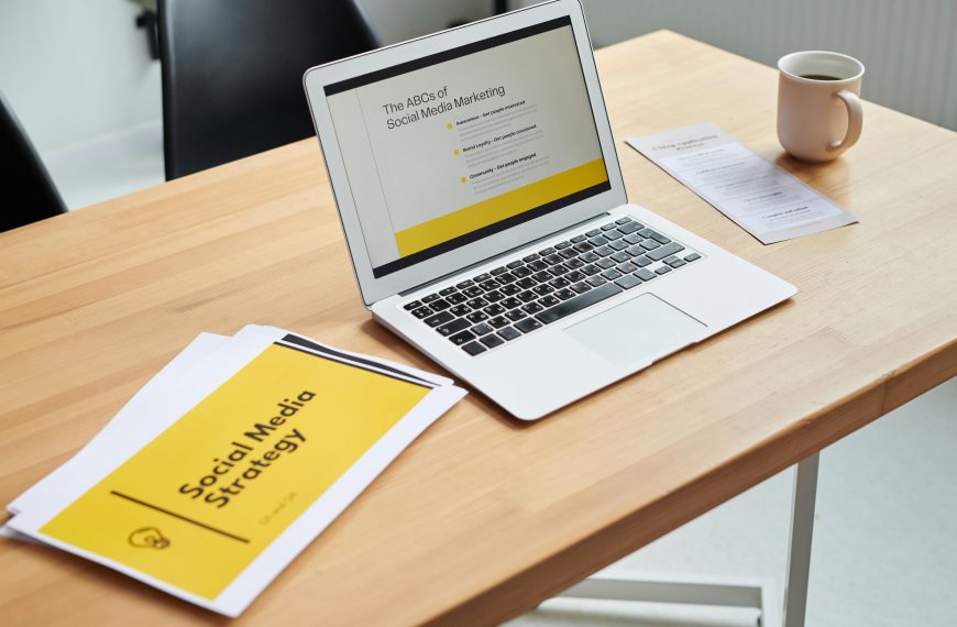 printed social media marketing strategy sheet next to a laptop on a desk