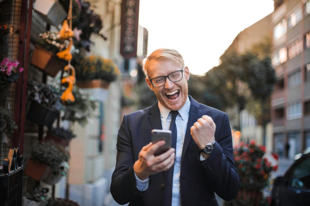 man in a suit holding a phone and making a victorious fist gesture