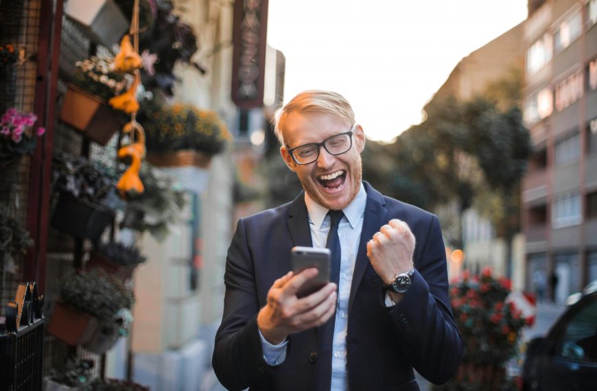 man in a suit holding a phone and making a victorious fist gesture